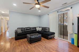 Living room with ceiling fan, ornamental molding, and wood-type flooring