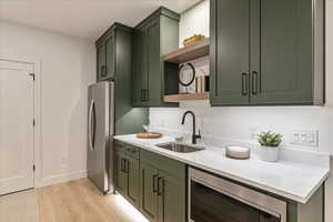 Kitchen with sink, stainless steel appliances, light hardwood / wood-style floors, and green cabinetry