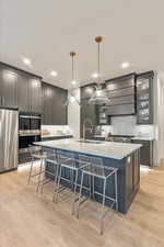 Kitchen with a large island, sink, fridge, decorative light fixtures, and wall chimney exhaust hood