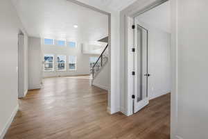 Hallway featuring a textured ceiling and light hardwood / wood-style floors