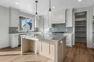 Kitchen featuring white cabinetry, decorative light fixtures, range, stainless steel dishwasher, and a kitchen island