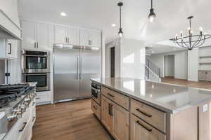 Kitchen featuring pendant lighting, stainless steel appliances, a center island, and white cabinets