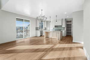 Kitchen with white cabinetry, decorative light fixtures, a center island, stainless steel appliances, and backsplash