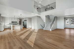 Unfurnished living room with a high ceiling, an inviting chandelier, and light hardwood / wood-style floors