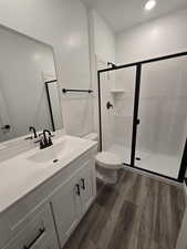 Bathroom with walk in shower, vanity, toilet, and hardwood / wood-style floors