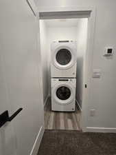 Laundry area featuring stacked washer / dryer and dark hardwood / wood-style floors