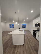 Kitchen with sink, an island with sink, white cabinets, and appliances with stainless steel finishes