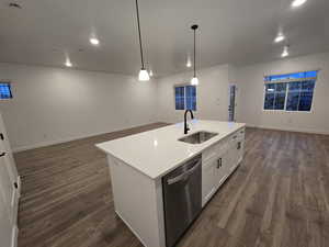 Kitchen featuring sink, a center island with sink, stainless steel dishwasher, pendant lighting, and white cabinets