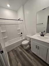 Full bathroom with vanity, hardwood / wood-style flooring, shower / tub combination, and toilet