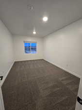 Empty room with a textured ceiling and dark carpet