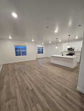 Unfurnished living room with hardwood / wood-style flooring, sink, and a textured ceiling