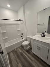 Full bathroom featuring hardwood / wood-style flooring, shower / bathtub combination, vanity, and toilet