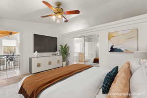 Bedroom with ceiling fan, light colored carpet, lofted ceiling, and ensuite bath