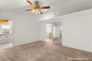 Unfurnished bedroom featuring ceiling fan, connected bathroom, a textured ceiling, vaulted ceiling, and light colored carpet