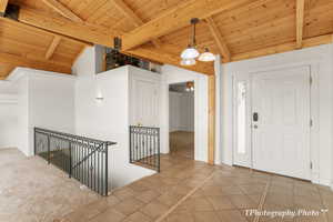 Carpeted foyer featuring vaulted ceiling with beams and wooden ceiling