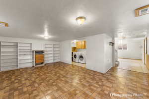 Laundry room featuring cabinets, separate washer and dryer, and a textured ceiling