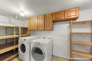 Laundry area featuring cabinets, washing machine and dryer, and light tile patterned floors