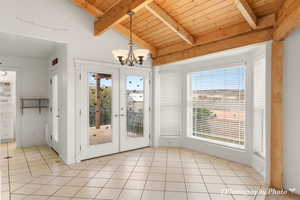 Doorway featuring light tile patterned flooring, french doors, a chandelier, lofted ceiling with beams, and wooden ceiling