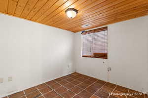 Spare room with wooden ceiling and dark tile patterned flooring