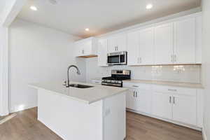 Kitchen with white cabinetry, sink, a center island with sink, and appliances with stainless steel finishes