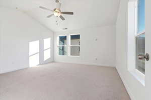 Carpeted spare room with ceiling fan and lofted ceiling