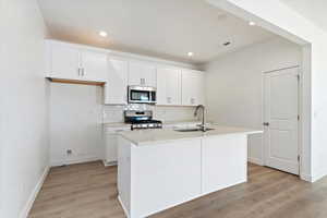 Kitchen with appliances with stainless steel finishes, sink, a center island with sink, and white cabinets