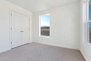 Unfurnished bedroom featuring light carpet and a closet