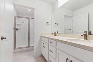 Bathroom with a shower with door, vanity, and tile patterned flooring