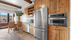 Kitchen with sink, tasteful backsplash, light tile patterned floors, stainless steel appliances, and beam ceiling