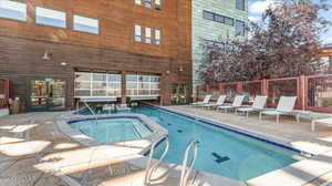 View of swimming pool with a hot tub and a patio