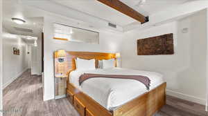 Bedroom with wood-type flooring and beam ceiling