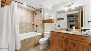 Full bathroom with shower / bathtub combination with curtain, vanity, and toilet