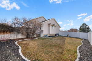 Back of property with cooling unit and a lawn