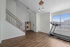 Exercise room with dark hardwood / wood-style flooring, high vaulted ceiling, and a textured ceiling