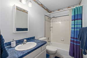 Full bathroom with shower / bathtub combination with curtain, vanity, and toilet