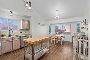 Kitchen with dishwasher, sink, light brown cabinetry, and decorative light fixtures