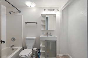 Full bathroom with sink, a textured ceiling, toilet, and shower / bath combination