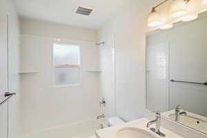 Full bathroom with tiled shower / bath, vanity, and toilet