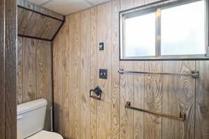 Bathroom featuring wooden walls and toilet