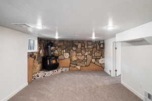 Basement featuring carpet and a wood stove