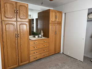 Primary bedroom with light carpet, ceiling fan.