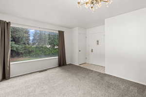 Carpeted front room featuring a notable chandelier