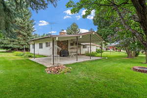 Rear view of house with a patio and a lawn. Mature fruit trees