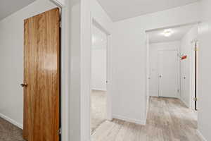 Hall featuring light wood-type flooring, & bright white paint