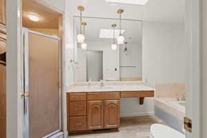 Full bathroom featuring hardwood / wood-style flooring, a skylight, vanity, and independent shower and bath