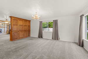 Carpeted front room with an inviting chandelier, and a wealth of natural light