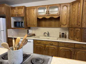 Kitchen featuring sink, white appliances, and decorative backsplash