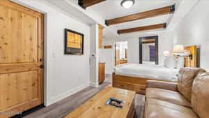 Bedroom featuring hardwood / wood-style floors, beam ceiling, and ensuite bath