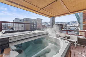 Snow covered deck with an outdoor hot tub and a mountain view