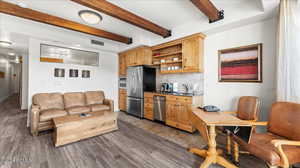 Kitchen with sink, backsplash, stainless steel appliances, beamed ceiling, and light brown cabinets